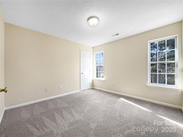 carpeted empty room featuring a textured ceiling