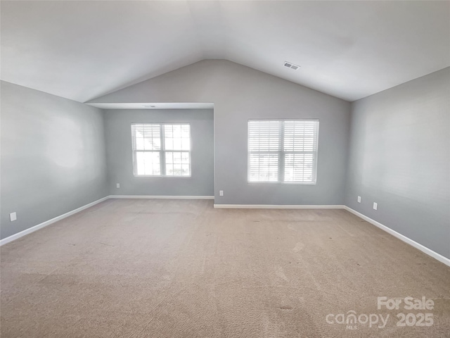 carpeted empty room featuring vaulted ceiling