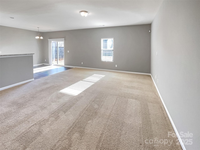 unfurnished room with light colored carpet and a notable chandelier