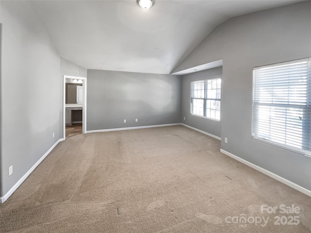 spare room featuring vaulted ceiling and light colored carpet