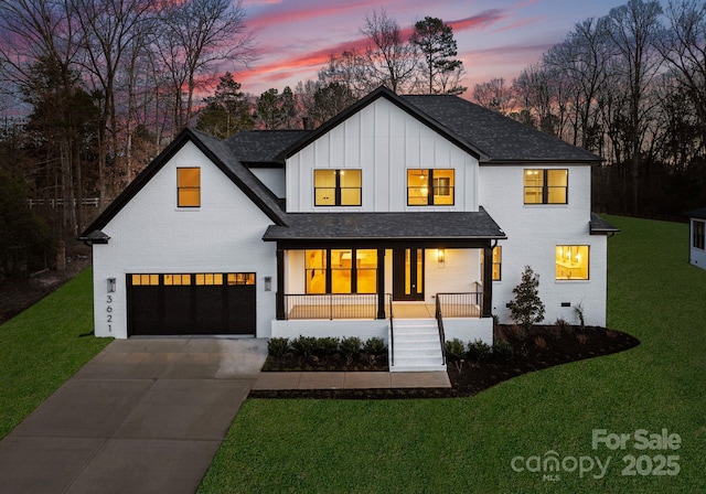 modern farmhouse with a garage, a lawn, and a porch