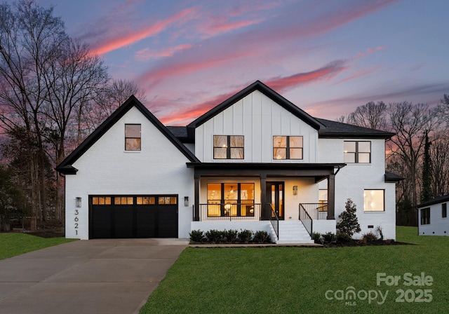 modern farmhouse style home with a garage, a lawn, and covered porch