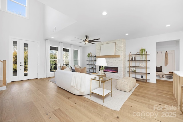 living room with a fireplace, ceiling fan, and light wood-type flooring