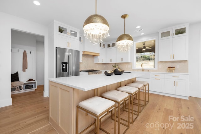 kitchen featuring a kitchen island, a breakfast bar area, high end refrigerator, and pendant lighting