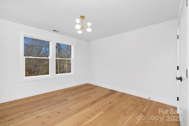 unfurnished room with hardwood / wood-style flooring and an inviting chandelier