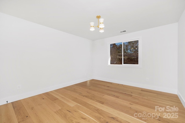 empty room featuring wood-type flooring and a chandelier