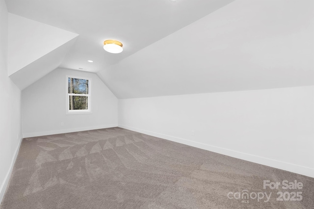 additional living space featuring light colored carpet and vaulted ceiling