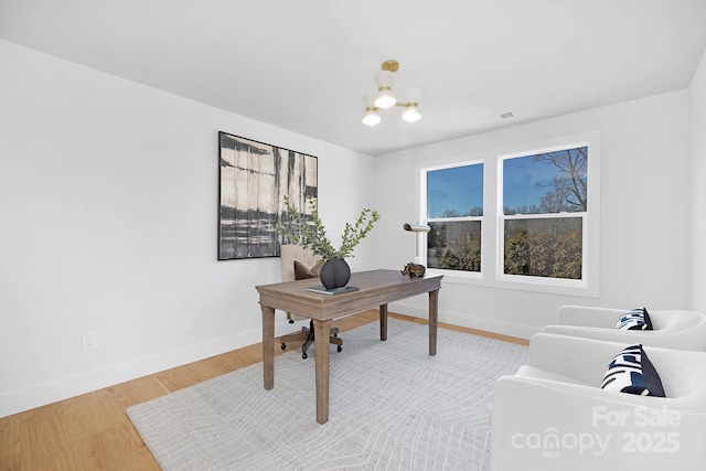 office with hardwood / wood-style floors and a chandelier