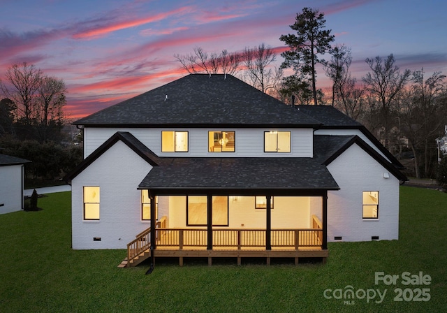 back house at dusk featuring a yard and a deck