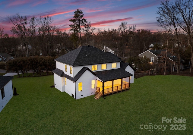 back house at dusk with a lawn