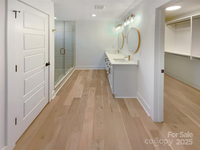 bathroom with vanity, wood-type flooring, and a shower with door