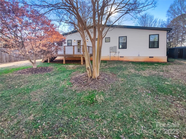 back of property featuring a wooden deck and a yard