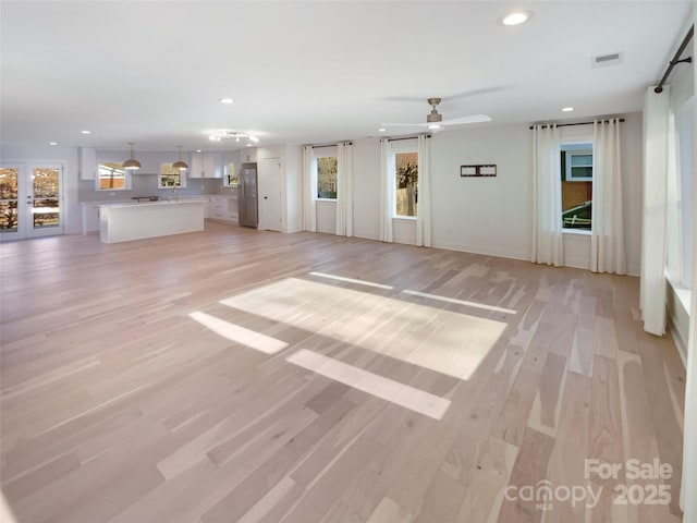 unfurnished living room with ceiling fan and light wood-type flooring