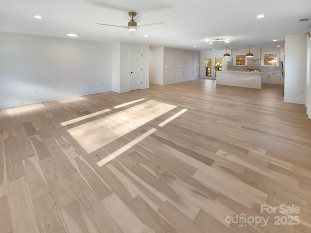 unfurnished living room with ceiling fan and light hardwood / wood-style flooring