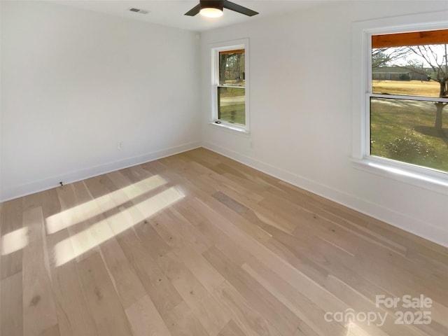 spare room featuring ceiling fan, a healthy amount of sunlight, and light hardwood / wood-style flooring