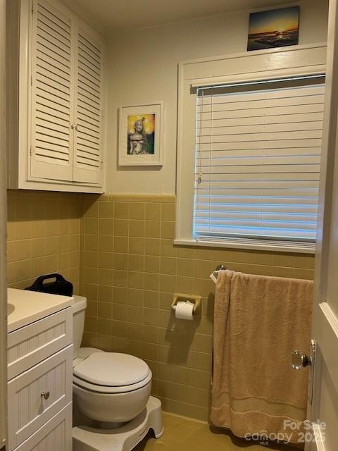 bathroom with toilet, vanity, tile walls, and tile patterned flooring