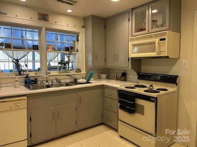 kitchen with sink, gray cabinetry, and white appliances