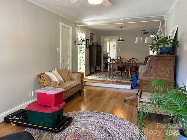 living room featuring ceiling fan, ornamental molding, and hardwood / wood-style floors