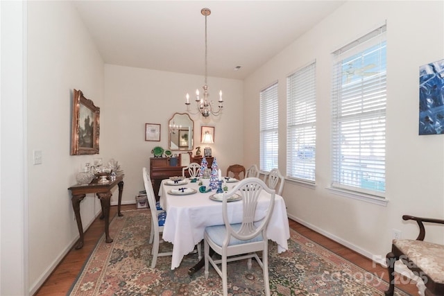 dining space with plenty of natural light, hardwood / wood-style floors, and an inviting chandelier