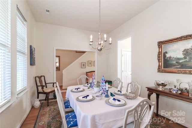 dining area with hardwood / wood-style flooring and a notable chandelier