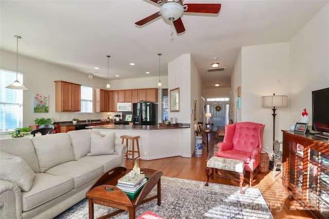 living room featuring ceiling fan and light hardwood / wood-style floors