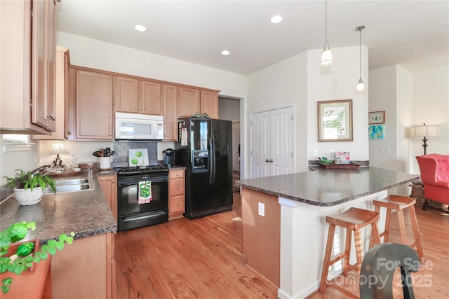 kitchen with tasteful backsplash, decorative light fixtures, black appliances, light hardwood / wood-style flooring, and sink