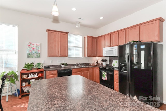 kitchen with sink, pendant lighting, light hardwood / wood-style flooring, and black appliances