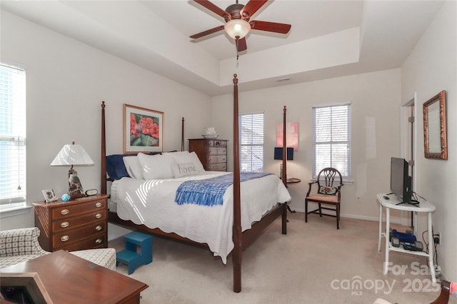 bedroom featuring ceiling fan, multiple windows, and a raised ceiling