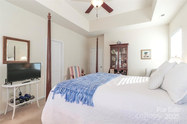 bedroom featuring light carpet, ceiling fan, and a raised ceiling