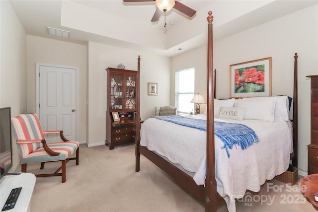 carpeted bedroom featuring ceiling fan and a raised ceiling