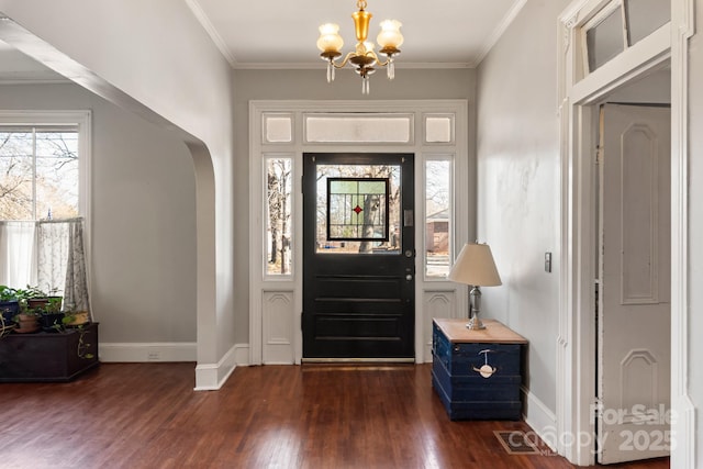 entrance foyer featuring dark wood-type flooring, crown molding, and a chandelier