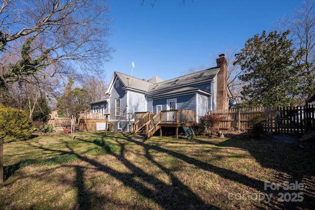 rear view of property featuring a wooden deck and a lawn