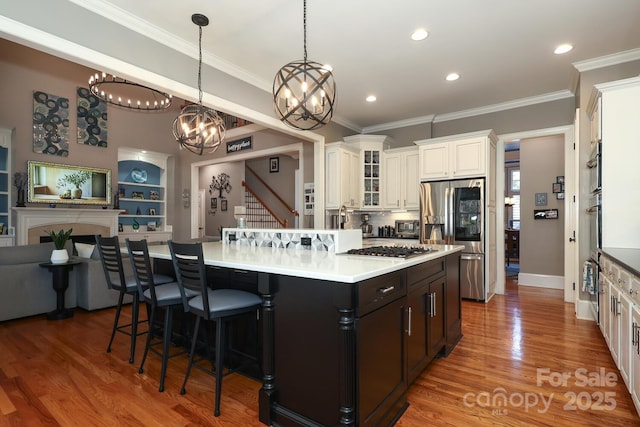 kitchen featuring pendant lighting, appliances with stainless steel finishes, a center island, a kitchen bar, and built in shelves