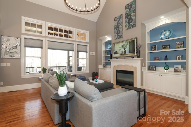 living room featuring high vaulted ceiling, wood-type flooring, and built in features