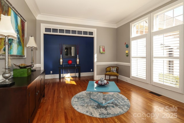 sitting room with dark wood-type flooring and crown molding