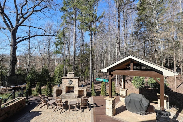 view of patio / terrace with area for grilling, a gazebo, a trampoline, and an outdoor stone fireplace