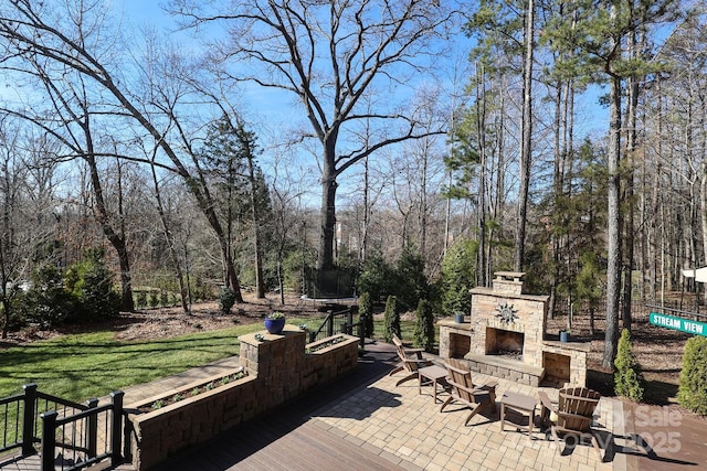 view of patio / terrace featuring a trampoline and an outdoor stone fireplace