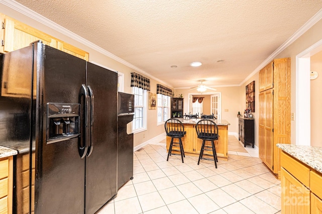 kitchen featuring ceiling fan, black fridge, a breakfast bar, crown molding, and light tile patterned floors