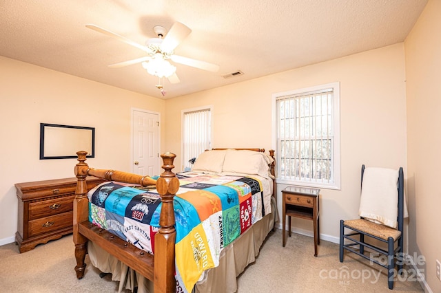 bedroom featuring ceiling fan, light colored carpet, and a textured ceiling