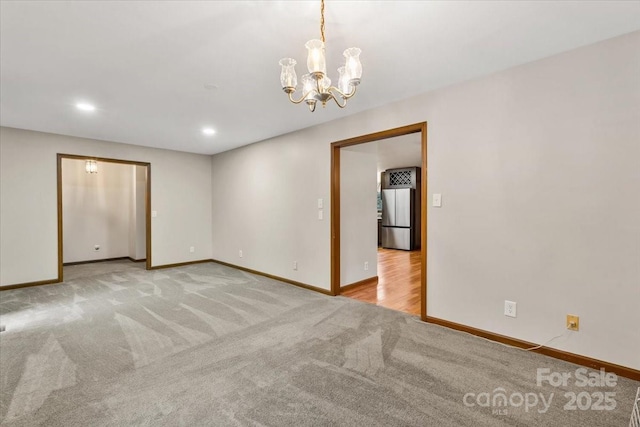 carpeted spare room featuring a notable chandelier