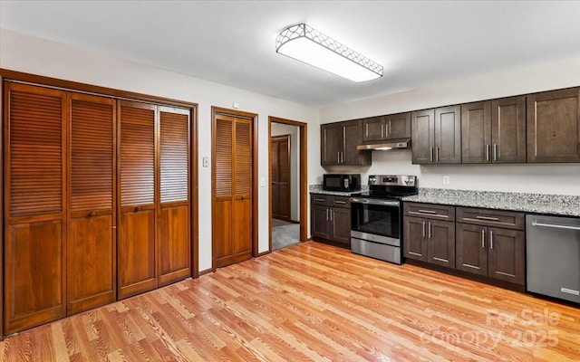 kitchen featuring light stone countertops, light hardwood / wood-style flooring, stainless steel appliances, and dark brown cabinets