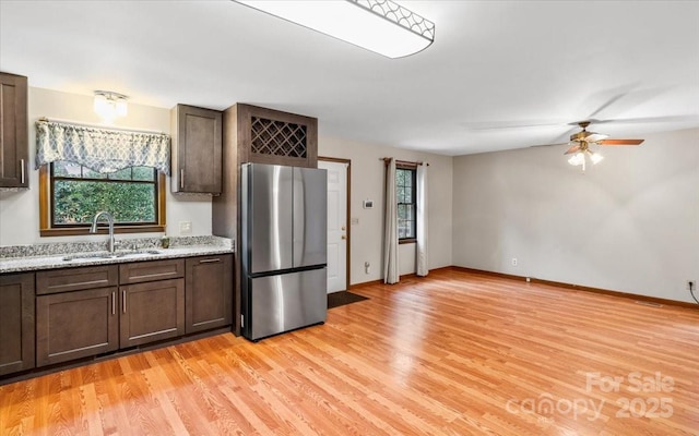 kitchen featuring ceiling fan, sink, stainless steel fridge, and light hardwood / wood-style flooring