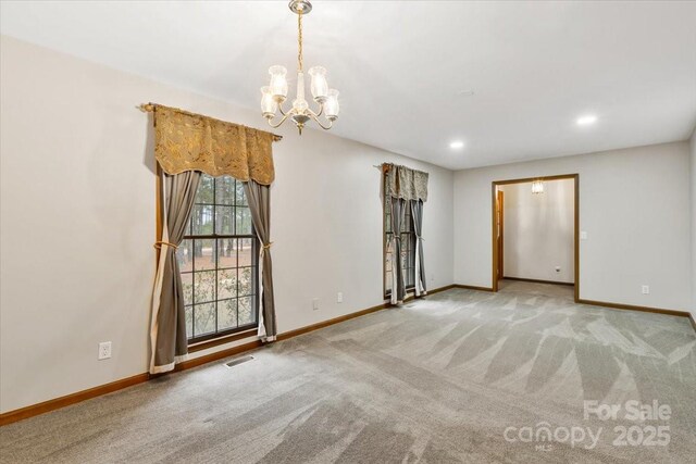 spare room with an inviting chandelier and light colored carpet