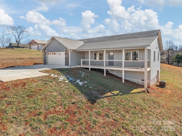 ranch-style home with a front yard, central air condition unit, covered porch, and a garage