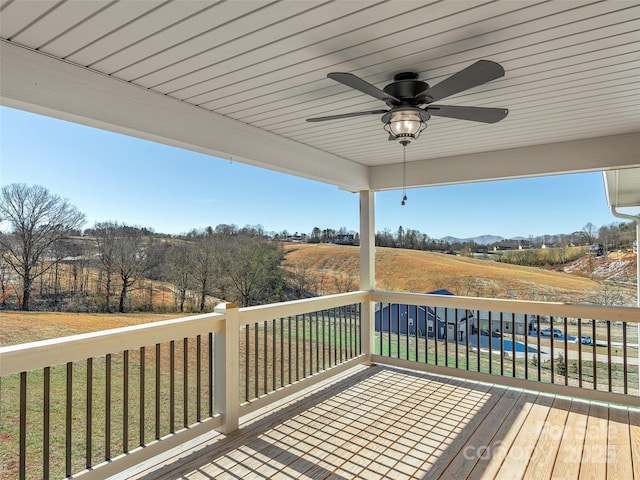 wooden deck with ceiling fan, a rural view, and a yard