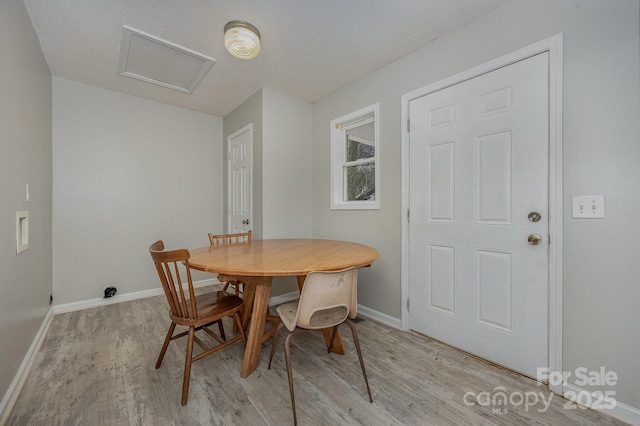 dining area featuring a textured ceiling and light hardwood / wood-style floors