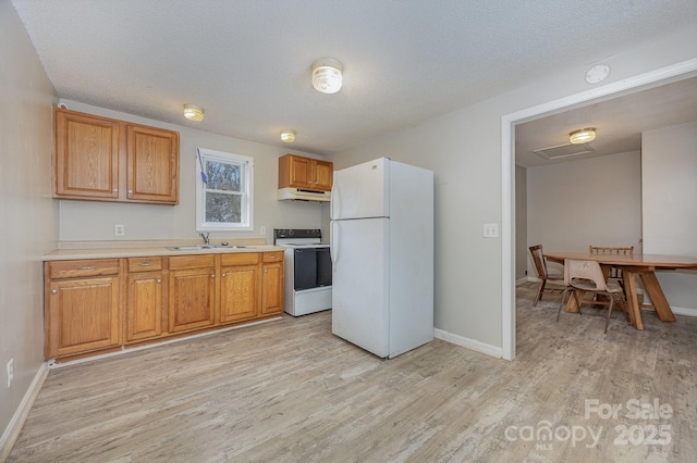 kitchen featuring sink, white appliances, light hardwood / wood-style flooring, and a textured ceiling