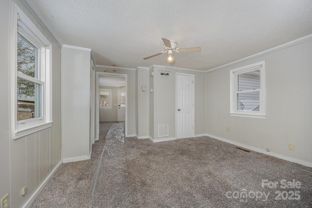 unfurnished bedroom featuring a textured ceiling, ornamental molding, ceiling fan, and carpet flooring