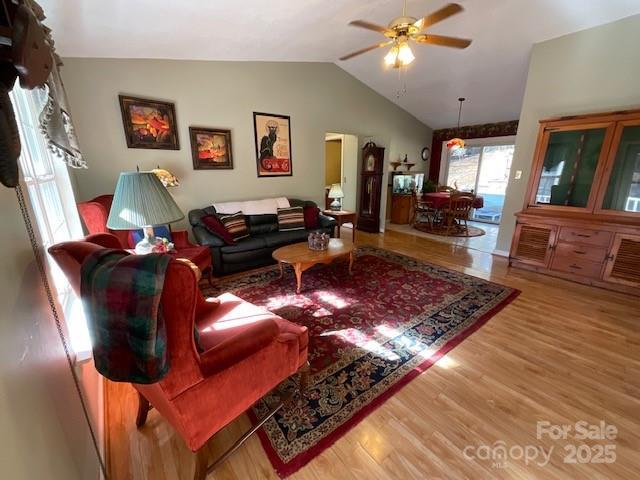 living room with hardwood / wood-style flooring, ceiling fan, and vaulted ceiling