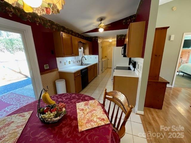 kitchen with lofted ceiling, light tile patterned floors, ceiling fan, backsplash, and black appliances